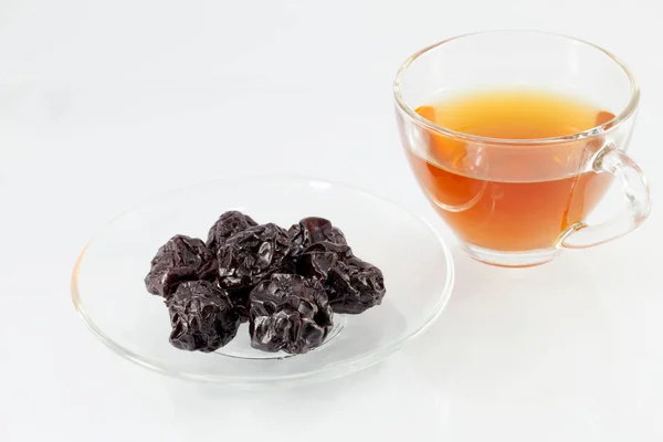 Сушеные сливы - чернослив в миске с чаем — стоковое фото
