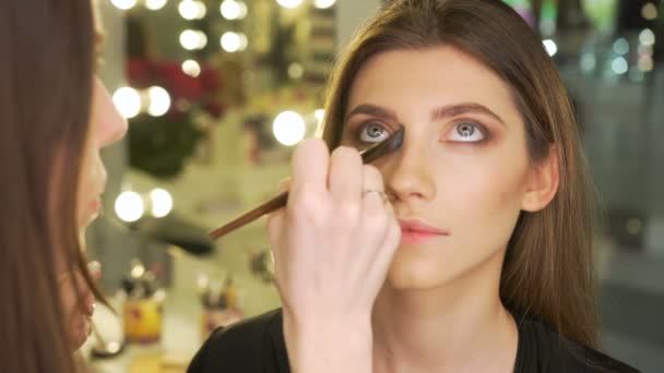 Maquillaje artista pone sombras en los ojos en el salón de belleza — Vídeo de stock