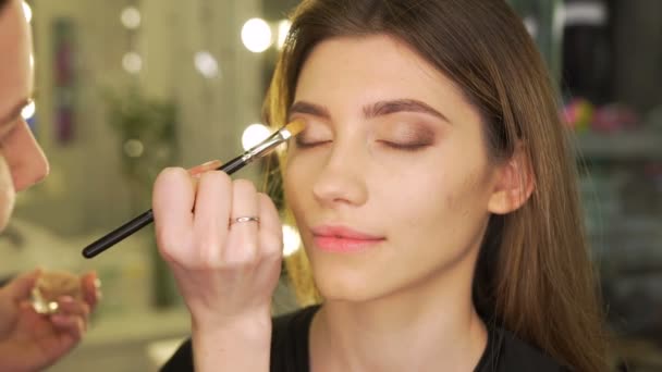 Maquillaje artista pone sombras en los ojos en el salón de belleza — Vídeo de stock