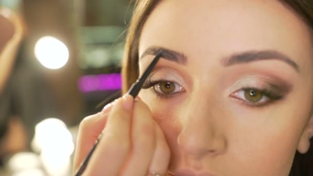 Make-up artist målar ögonbrynen modellen i skönhetssalongen. Närbild — Stockvideo