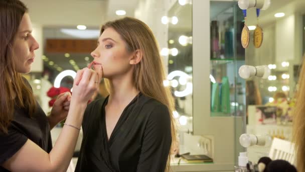 Make-up artist målar läpparna av modellen i skönhetssalongen. — Stockvideo