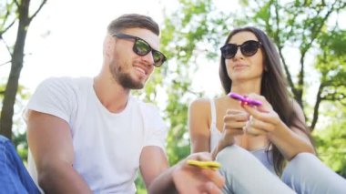 Genç çift parkta bir el spinner ile eğleniyor. Yaz yaşam tarzı kavramı