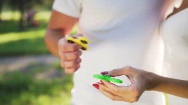 Genç çift parkta bir el spinner ile eğleniyor. Yaz yaşam tarzı kavramı