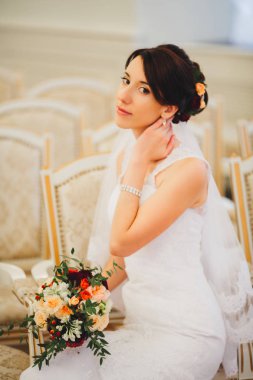 Gelinlikli genç gelin elinde buket tutuyor.