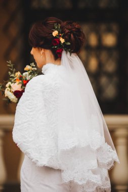 Gelinlikli genç gelin elinde buket tutuyor.