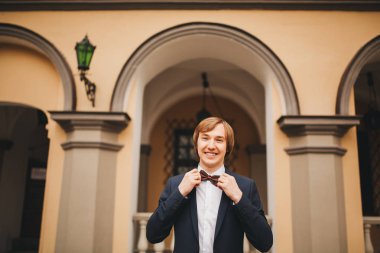 Muhteşem gülümseyen damat. Bir paketi kapalı pencere pervazına üzerinde oturan bir ilik ile yakışıklı adam