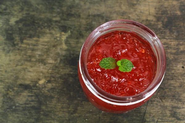 Verse aardbeien jam in glazen fles met muntblad — Stockfoto