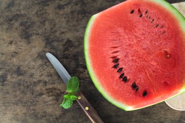 Kırmızı karpuz bir bütün ve nane yaprağıyla dilimlenmiş.