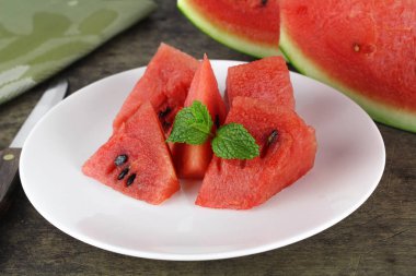 Kırmızı karpuz bir bütün ve nane yaprağıyla dilimlenmiş.