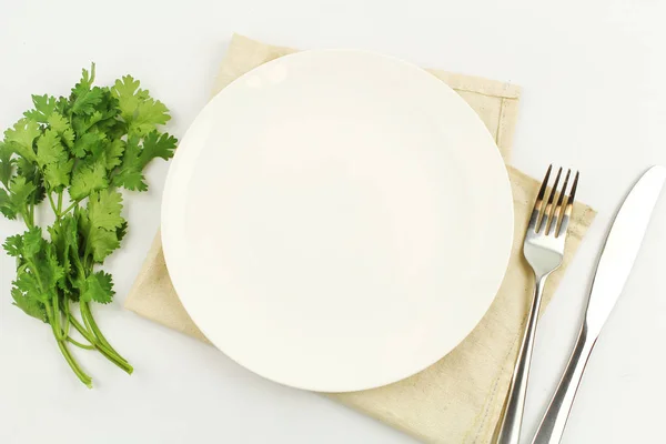 Άσπρο πιάτο σε λευκό φόντο διακόσμηση με κουτάλι και πιρούνι — Φωτογραφία Αρχείου