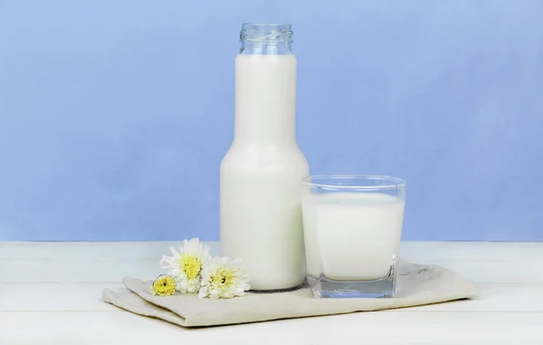Egy üveg tejet és pohár tej, egy fából készült asztal, a háttér — Stock Fotó