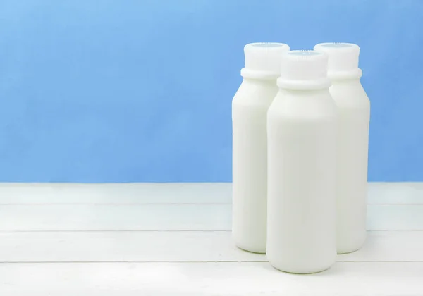 Uma garrafa de leite e copo de leite em uma mesa de madeira em um fundo — Fotografia de Stock