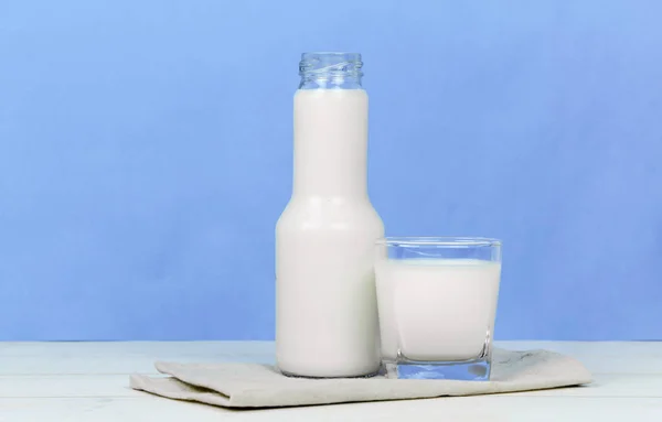Бутылка молока и стакан молока на деревянном столе на заднем плане — стоковое фото
