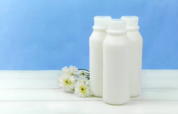 En flaska mjölk och glas mjölk på ett träbord på en bakgrund — Stockfoto