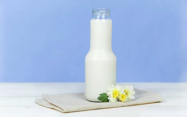 Una bottiglia di latte e un bicchiere di latte su un tavolo di legno su uno sfondo — Foto Stock