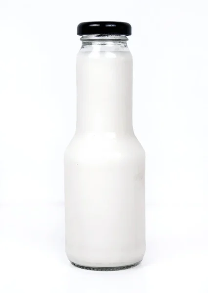 Une bouteille de lait et un verre de lait sur une table en bois sur un fond — Photo