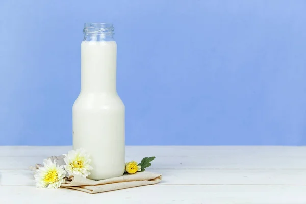 En flaska mjölk och glas mjölk på ett träbord på en bakgrund — Stockfoto