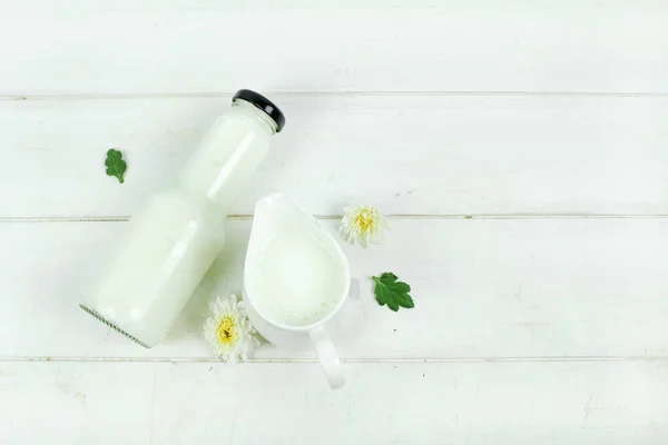 En flaske mælk og glas mælk på et træbord på en baggrund - Stock-foto