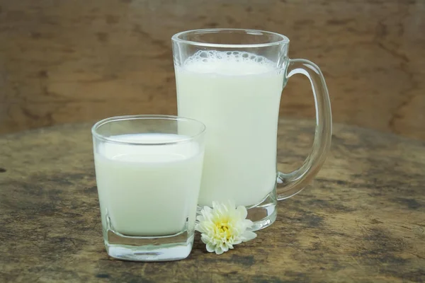 Una bottiglia di latte e un bicchiere di latte su un tavolo di legno su uno sfondo — Foto Stock