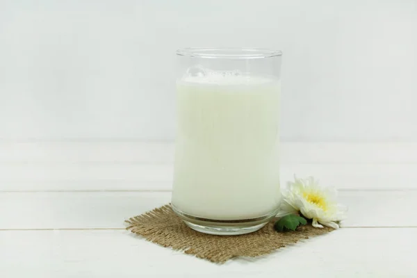 Een fles melk en glas melk op een houten tafel op een achtergrond — Stockfoto