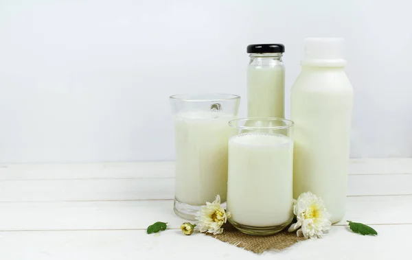 Una botella de leche y un vaso de leche sobre una mesa de madera sobre un fondo —  Fotos de Stock
