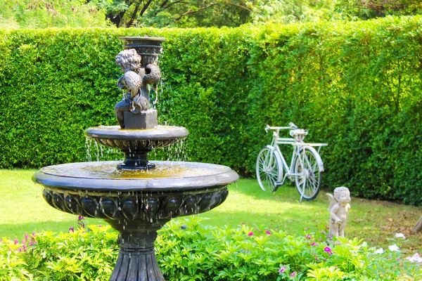 Сад с небольшим фонтаном и каменной скамейкой зеленые газоны кустарники деревьев — стоковое фото