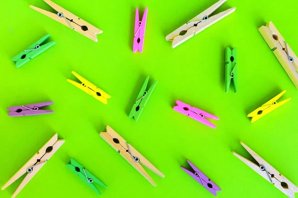 colorful wood clothes pin, paper clip on green background