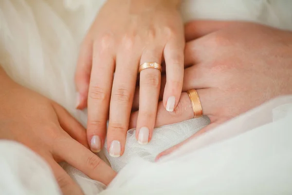 Anneaux de mariage sur quelques mains, robe blanche de mariée — Photo