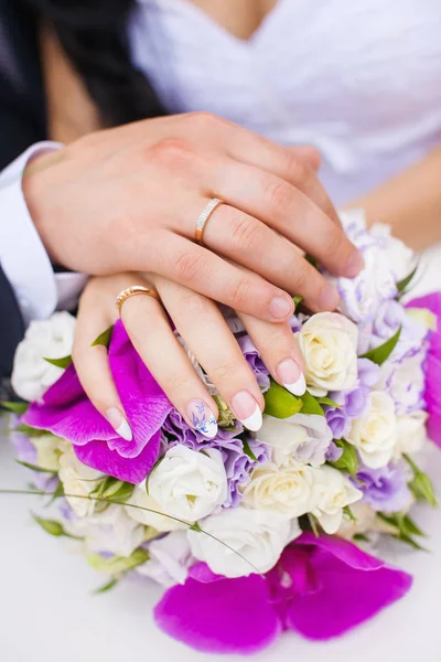 Anéis de casamento em mãos de casal no buquê de noiva . — Fotografia de Stock