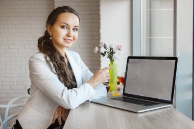Güzel kız onun dirsekler masada dizüstü bilgisayar ile eğilir