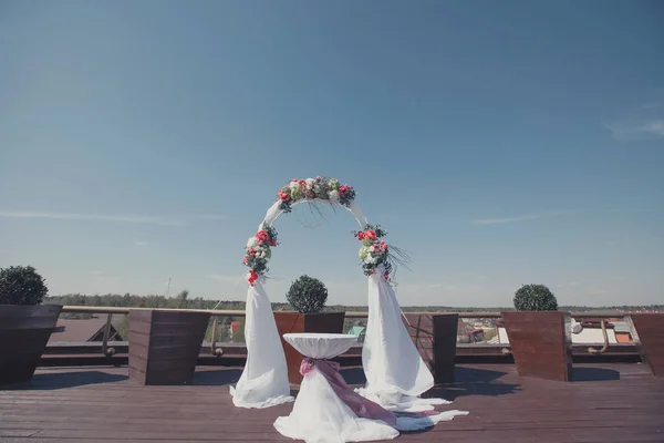 Arco de boda cenador con tela blanca y flores. Mesa de ceremonia —  Fotos de Stock