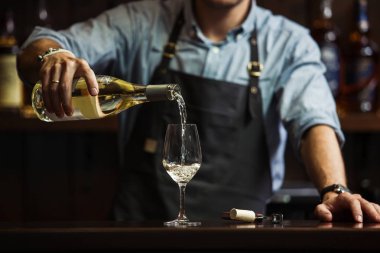 Erkek sommelier beyaz şarap uzun saplı kadehlerin dökme.