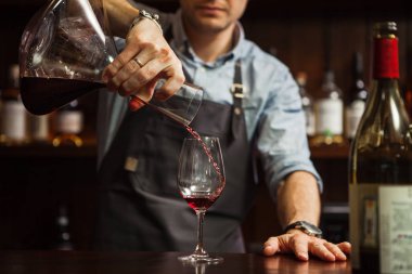 Şarap garsonu karıştırma kabından bardağa şarap dolduruyor. Erkek garson.