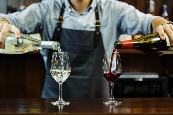 男侍酒师倾吐的红色和白色成长茎的酒杯的酒 — 图库照片