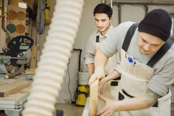 İki adam ahşap işçiliği makinesinde kereste tutuyor. — Stok fotoğraf