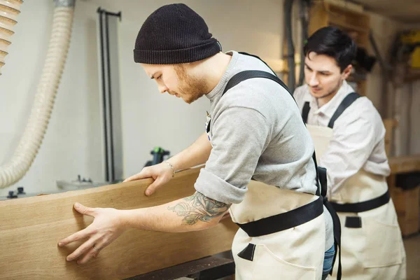 Zwei Männer halten Holz an Holzbearbeitungsmaschine — Stockfoto