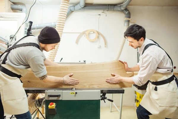 Zwei Männer halten Holz an Holzbearbeitungsmaschine — Stockfoto