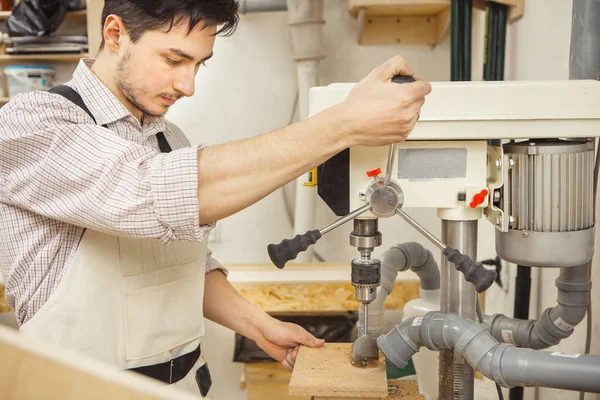 Brunette man verveeld houten plank op het boren van de machine — Stockfoto