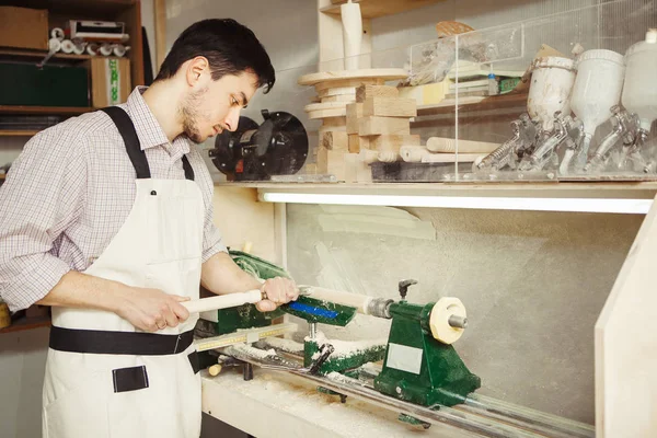 Jovem turner se envolve em escultura de madeira no torno para madeira — Fotografia de Stock