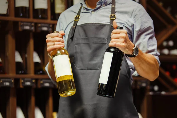 Joven sommelier sosteniendo botella de vino tinto en bodega — Foto de Stock