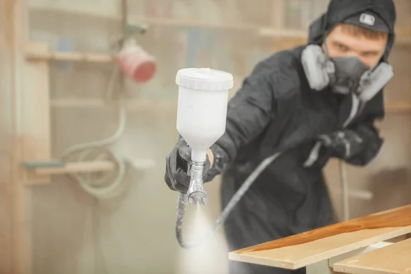 Hombre en respirador máscara pintura tablones de madera en el taller. — Foto de Stock