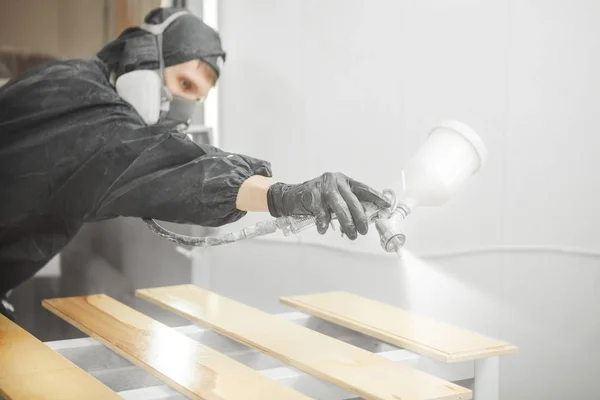 Hombre en respirador máscara pintura tablones de madera en el taller. — Foto de Stock
