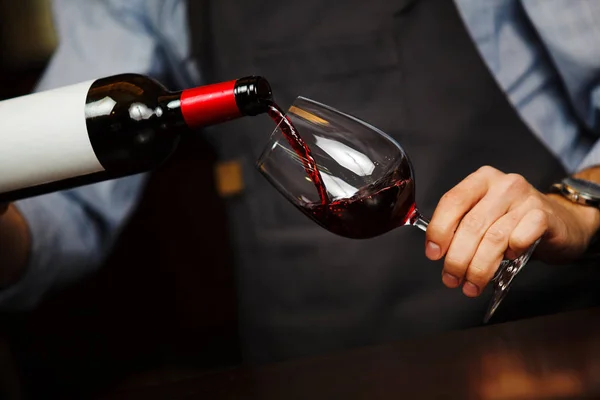 Homem derramando vinho em vinho, mão masculina segurando garrafa — Fotografia de Stock