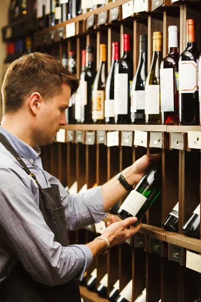 Düşünceli uzman şarap raflara arka plan üzerinde şarap yapımı.