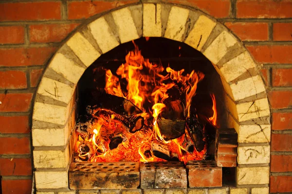 Brick fireplace with burning fire, red flame from woods.