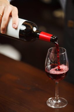 Garson şarap kadehine kırmızı şarap dolduruyor. Sommelier alkollü içecek doldurur.
