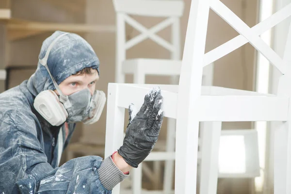 Hombre comprueba la uniformidad de la aplicación de pintura en la máscara respiratoria. Aplicación de retardante de llama que garantiza la protección contra incendios, pulverización sin aire . — Foto de Stock