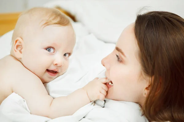 Madre juega con el bebé pelo rubio, bebé tiene mejillas regordetas — Foto de Stock