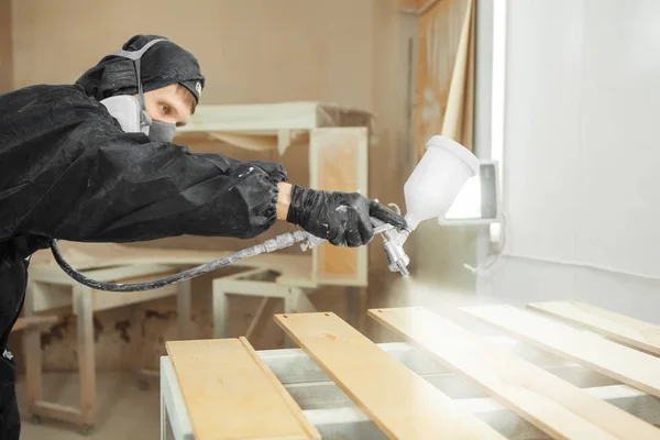 Man i respirator mask måla trä plankor på verkstad. — Stockfoto