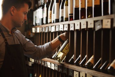 Düşünceli uzman şarap raflara arka plan üzerinde şarap yapımı.